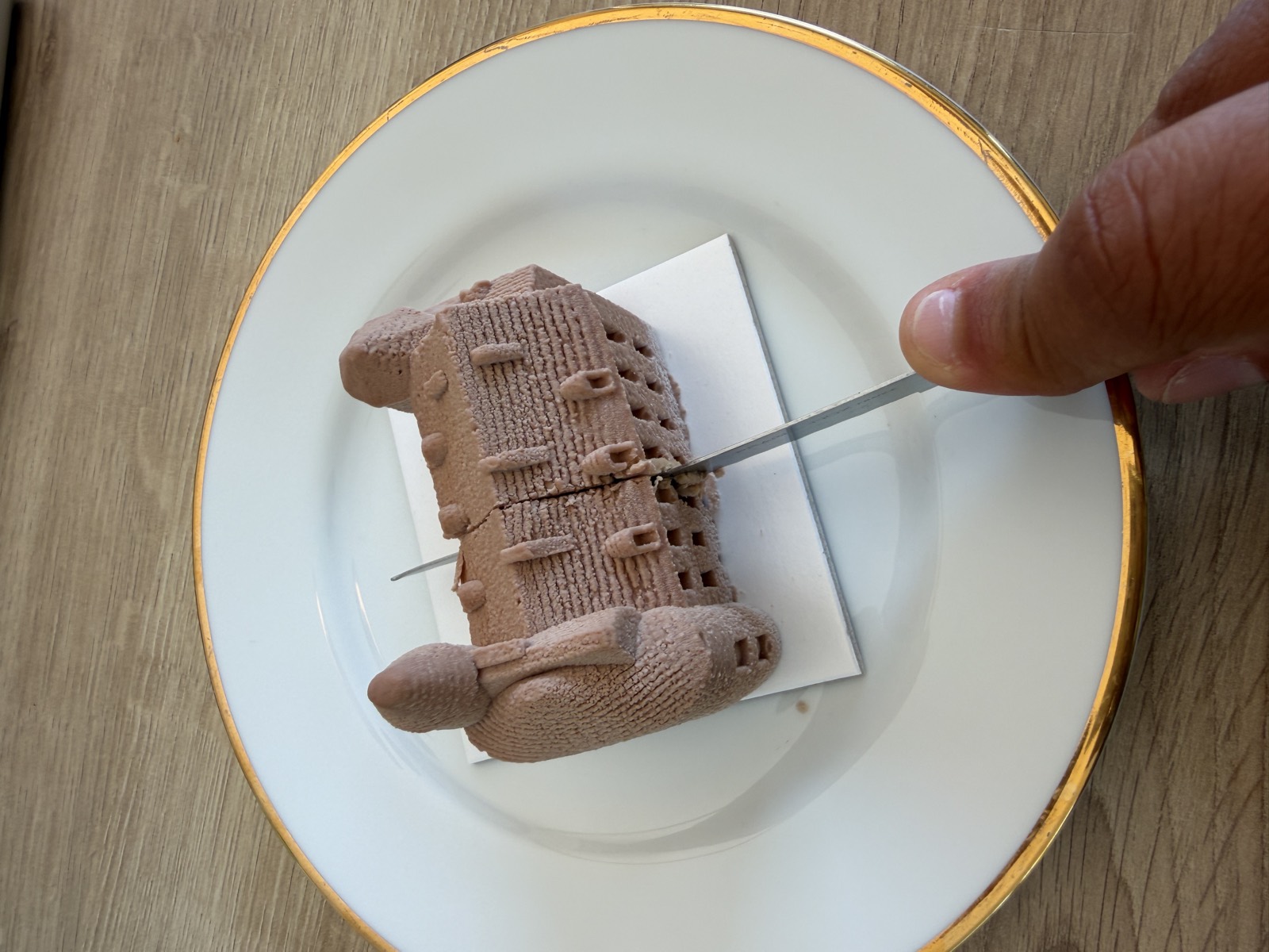 Le Château de Pont-l'Abbé de Mocha Blanc, entier sur une assiette à filet doré, au moment de le couper